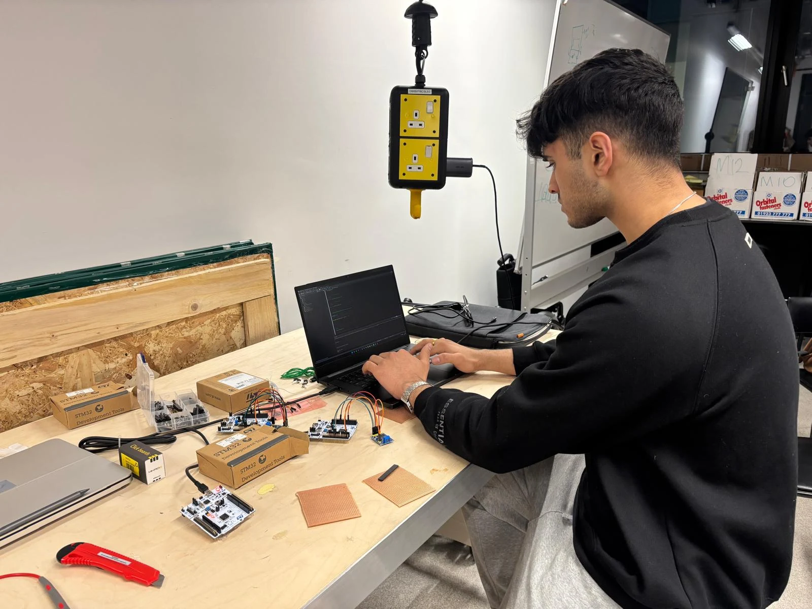 Rohan developing embedded electronics at a workbench with STM32 boards